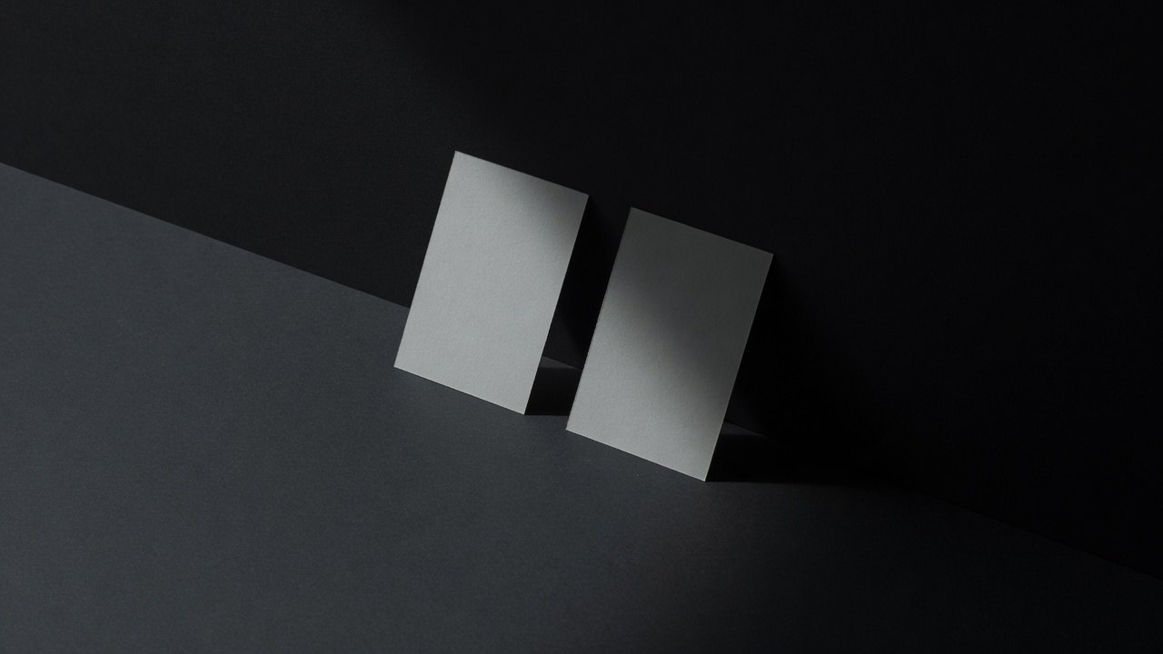 Two identical pale cards standing side by side, one lit and one in shadow.